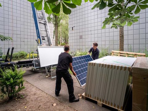 Zwei Personen tragen Solarpanel bei Installation