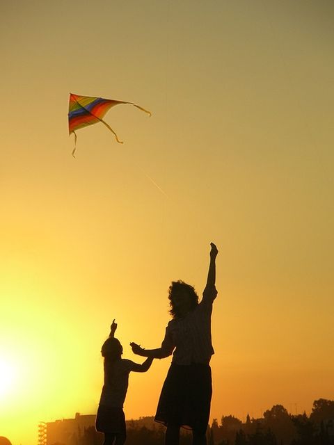 Bild Mutter und Kind lassen einen Drachen im Sonnenuntergang steigen