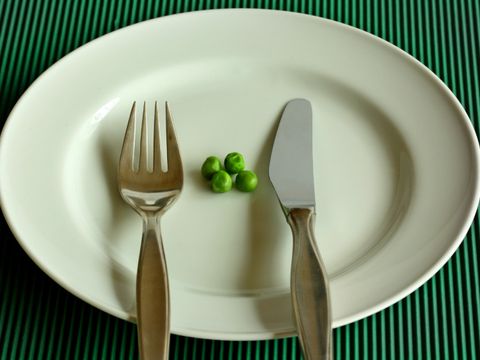 Ein Teller mit Messer, Gabel und vier Erbsen