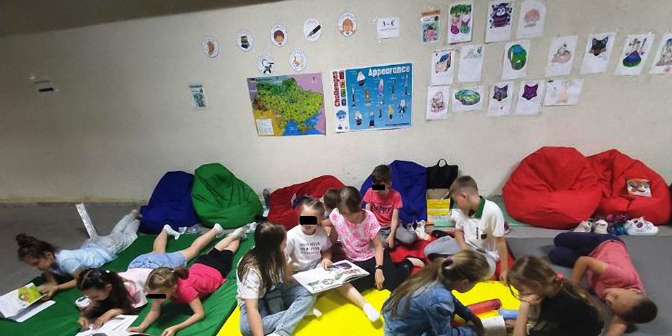 Kinder lesen in einem Schutzraum in Kyjiw-Darnyzja