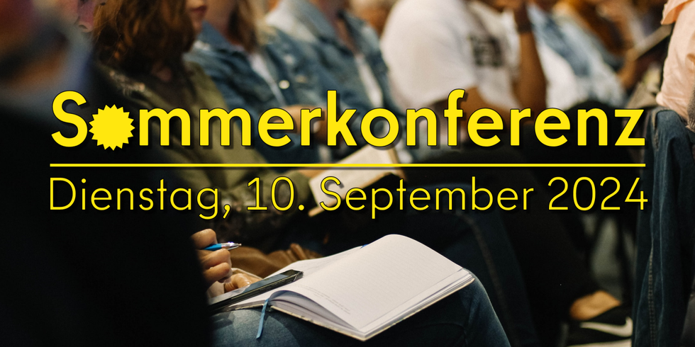 Schriftzug "Sommerkonferenz - Dienstag, 10. September 2024" vor dem Publikum einer Veranstaltung