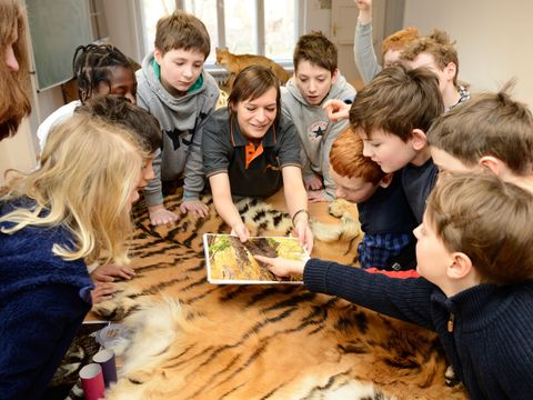 Gruppe von Kindern zusammen mit einer Erwachsenen stehen um einen Tisch und agieren miteinander