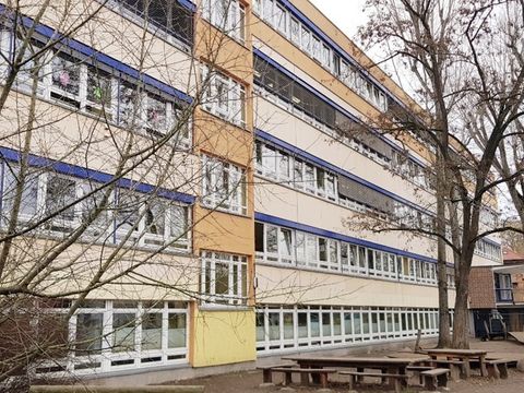 Schulhaus der Grundschule unter den Bäumen mit Bäumen rechts und links