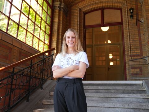 Die Protagonistin Emma steht auf einer Treppe und lacht in die Kamera