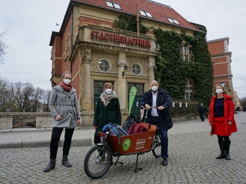 Bildvergrößerung: abgebildete Personen v.l.n.r.:Ina Wolter, Leiterin der Bezirkszentralbibliothek, Insa Ahlers, Klimaschutzmanagerin der Leitstelle für Nachhaltigkeit und Klimaschutz, Frank Bewig, Bezirksstadtrat für Bauen, Planen und Gesundheit, Corina Weber, Leiterin der Leitstelle für Nachhaltigkeit und Klimaschutz mit einem Lastenfahhrad vor der Stadtbücherei in der Altstadt Spandau