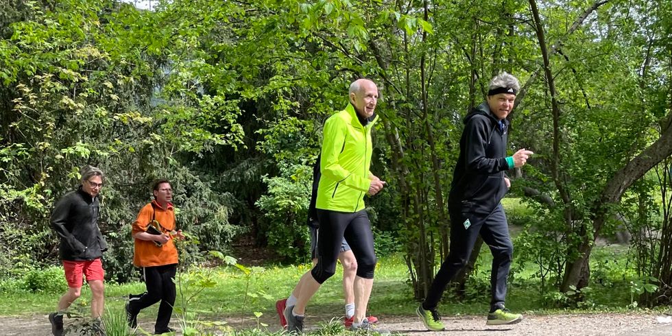 Fünf Menschen joggen durch einen Park.