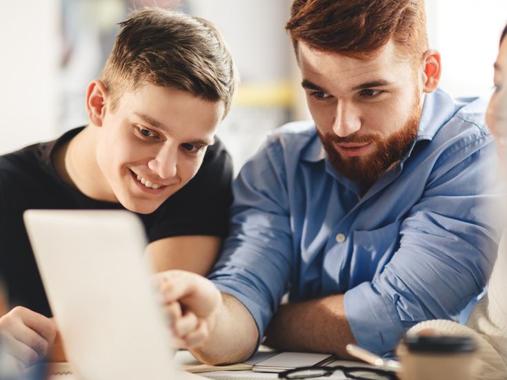 Drei Studierende schauen gemeinsam auf ein Tablet 