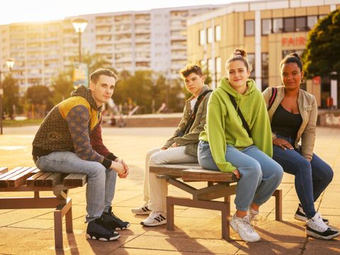 Vier junge Menschen sitzen auf einer Bank