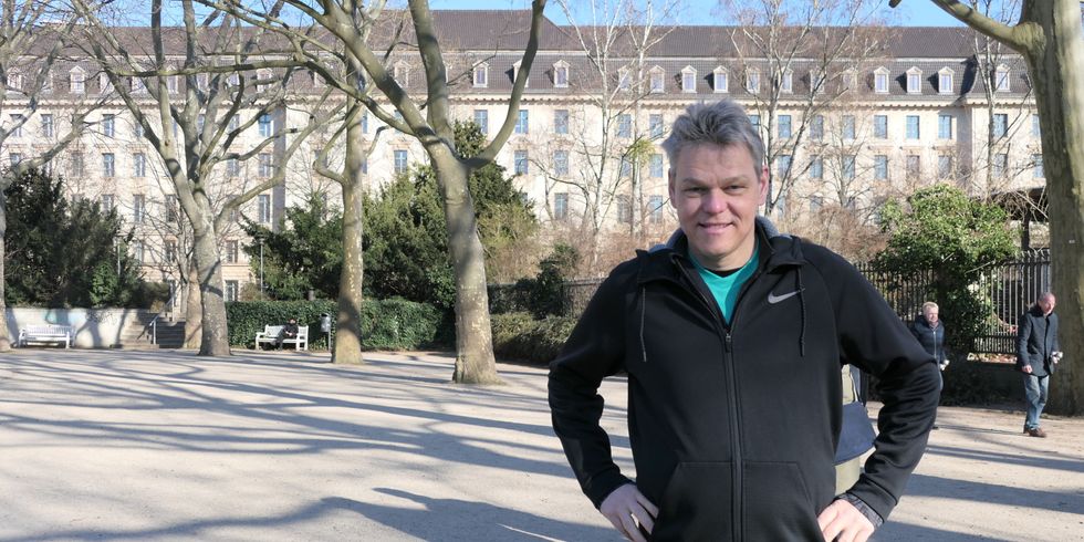 Ein Mann in einer Joggingjacke steht draußen in einem Park.