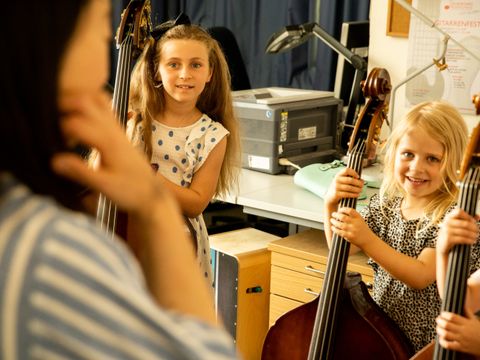 Bildvergrößerung: Zwei Kinder lernen Streichinstrumente bei der Instrumentenrally kennen