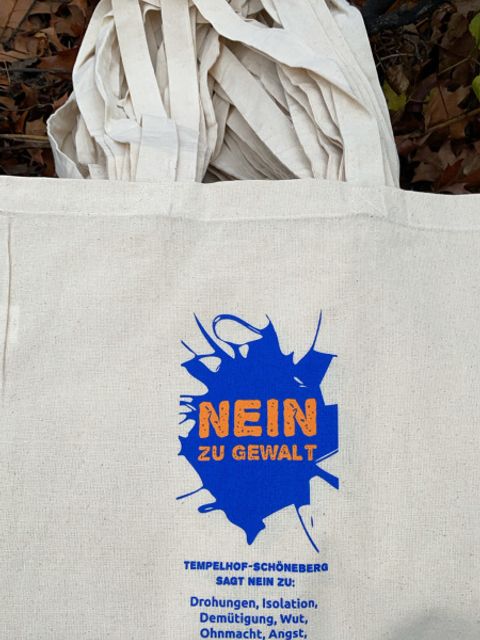 Bildvergrößerung: Ein Jutebeutel mit der Aufschrift: Nein zu Gewalt, Tempelhof-Schöneberg sagt Nein zu Drohungen, Isolation, Demütigung, Wut, Ohnmacht, Angst, Zwang, Gewalt, Einschüchterung, Unsicherheit, Verletzung, Leid. 25.11. Internationale Tag gegen Gewalt an Frauen.