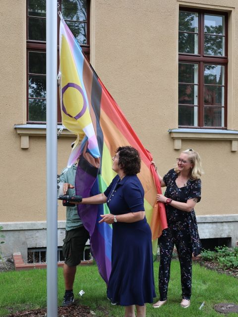 Bildvergrößerung: Bezirksbürgermeisterin Maren Schellenberg hisste zusammen mit Yasmine-Blanche Werder vom LSVD Berlin-Brandenburg die Progress Pride Flag