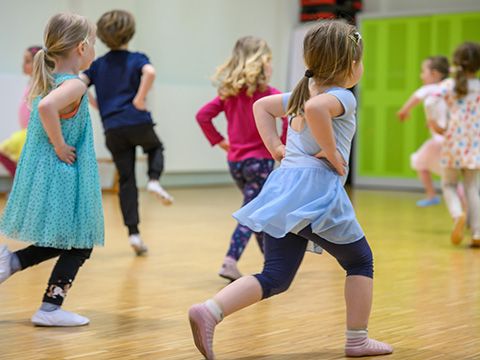 Kinder rennen im Kreis in der Turnhalle, im. Kurs Tanz und Bewegung für Kinder