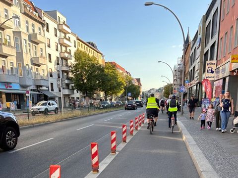 Bildvergrößerung: Menschen fahren auf Fahrrädern auf einer geschützten Radverkehrsanlage.