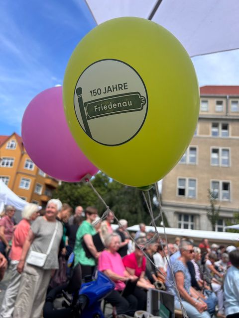 Bildvergrößerung: ein Luftballon mit der Aufschrift "150 Jahre Friedenau" vor einem gut besuchter Platz 