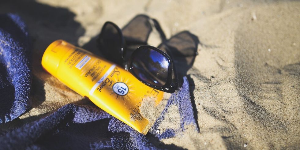 Sonnenbrille, Sonnencrem und ein Handtuch am Strand