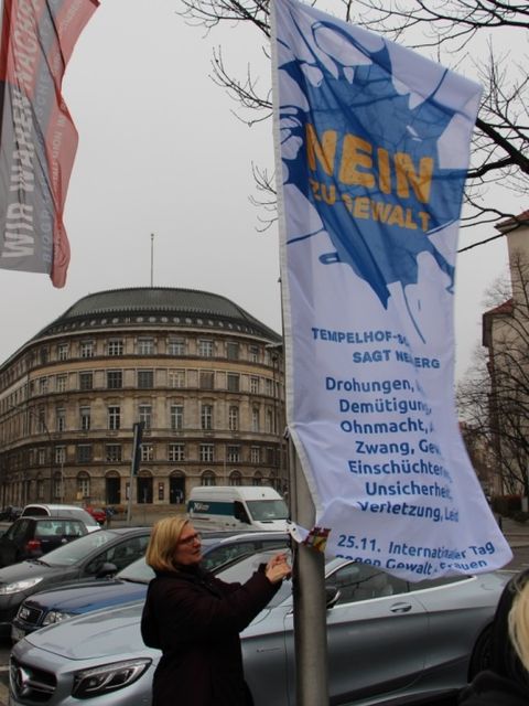 Bildvergrößerung: Frau hisst die bezirkliche Antigewaltfahne