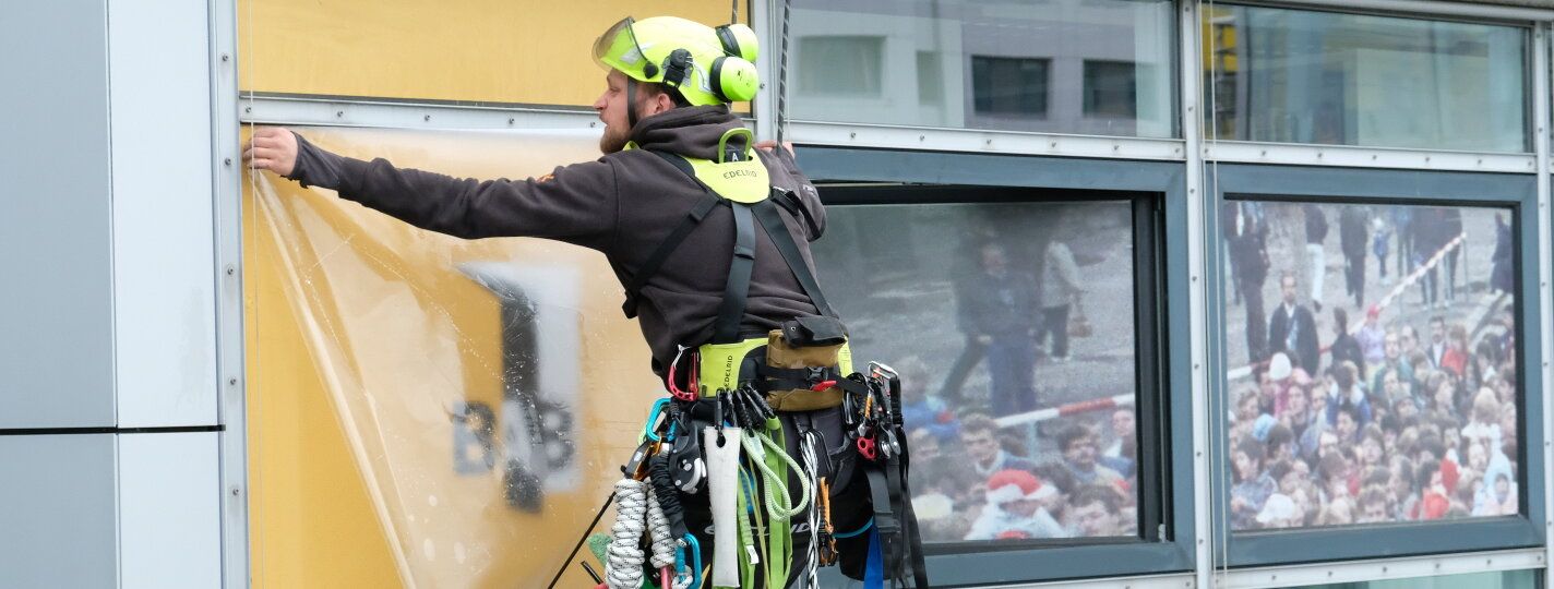 Fassadenkletterer bringen Fensterfolie an