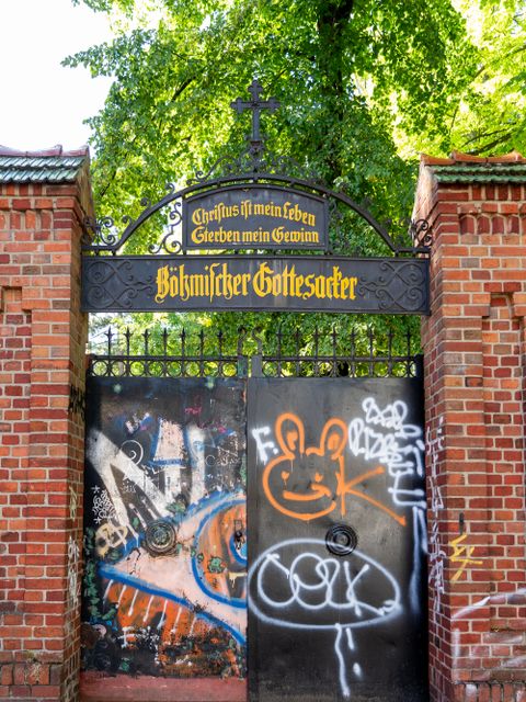 Zugangstor zum Böhmischen Gottesacker mit historischem Torbogen und Graffiti auf dem Tor