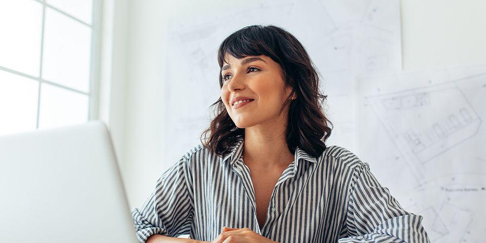 Frau mit Laptop vor ihr, im Hintergrund Architekturpläne