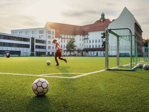 Kind spielt mit einem Ball auf einem Sportplatz