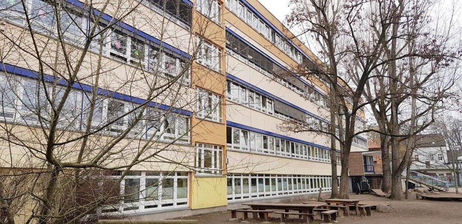 Schulhaus der Grundschule unter den Bäumen mit Bäumen rechts und links