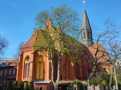 Kirche aus rotem Backstein mit blauem Himmel darüber