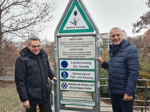 Bildvergrößerung: Zwei Männer stehen neben einem Parkschild für den Mezitli-Park.