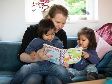 Eine Frau liest zwei Kindern vor