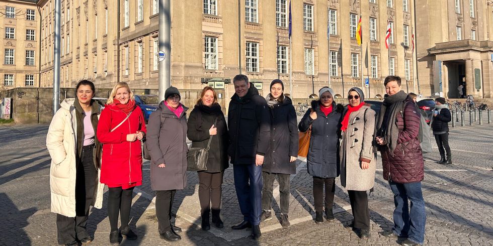 Acht Frauen und ein Mann stehen vor dem Rathaus und schauen in die Kamera