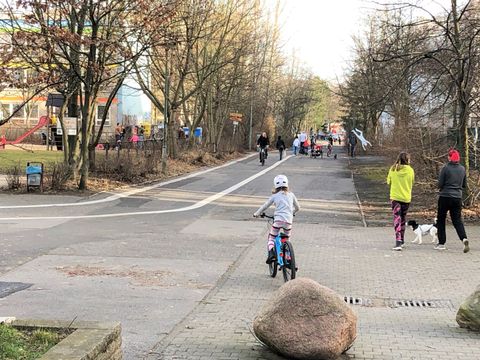 Promenade mit Radstreifen, Findling als Poller, Kinder und Erwachsene, Hunde, Radfahrende