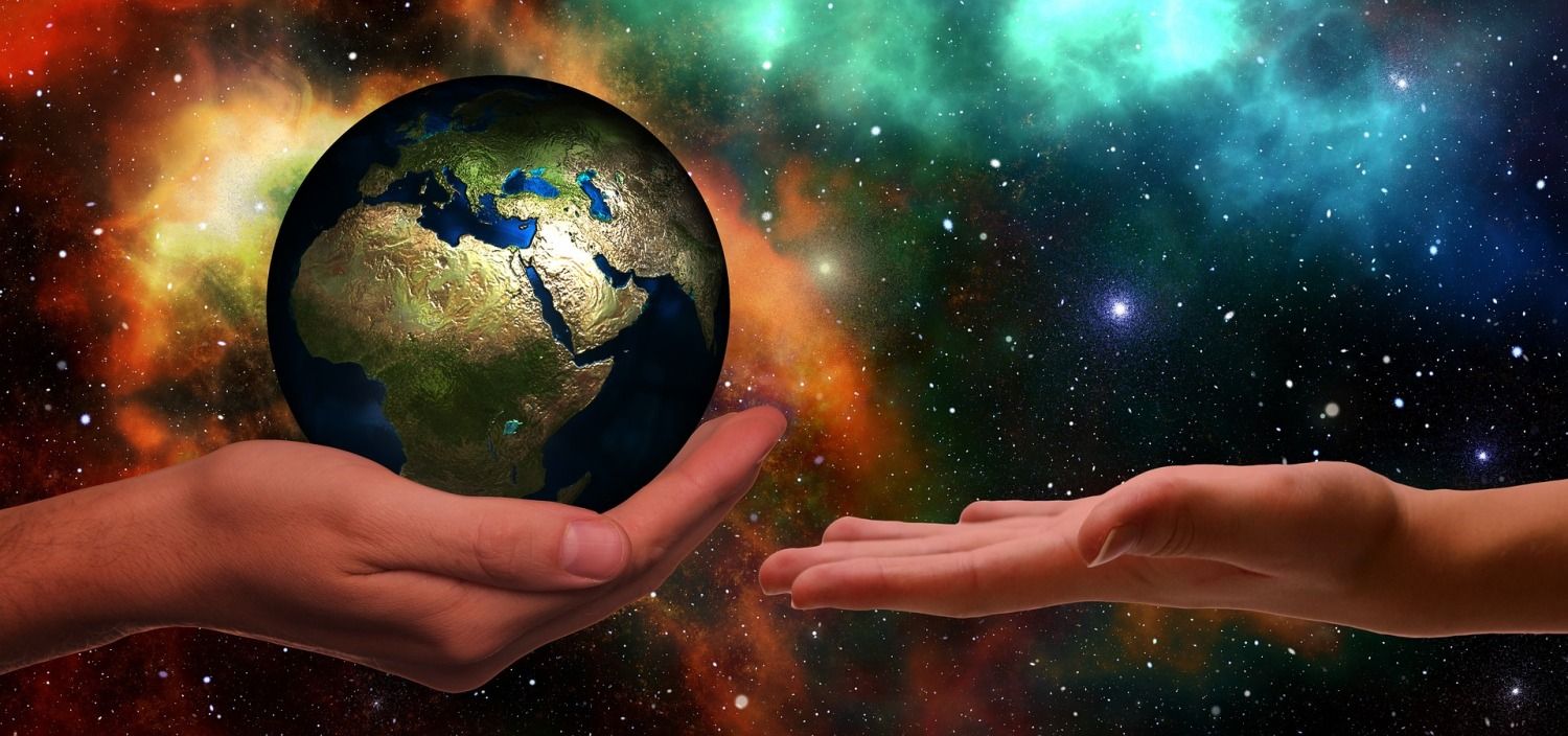 Hand hält Globus ähnlich einer großen Murmel mit goldenen Kontinenten und reicht sie einer weiteren ausgestreckten Hand.