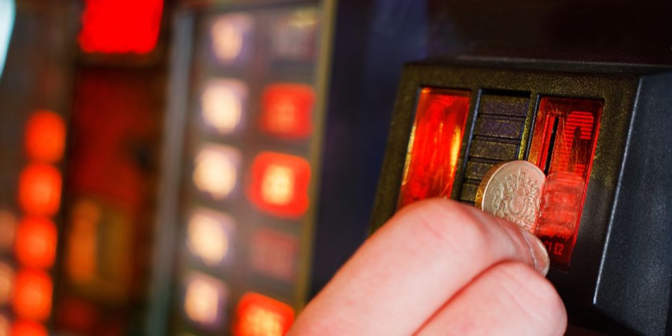 Eine Person wirft eine Münze in einen Spielautomat