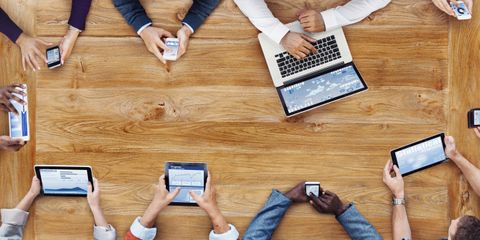 Blick von oben auf eine Gruppe von Menschen mit Tablets, Smartphones und Computern