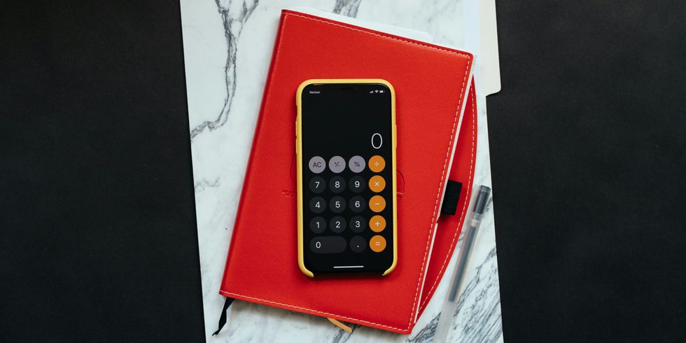Die Fotografie zeigt ein Smartphone mit Taschenrechner-App, das auf einer Tasche liegt.