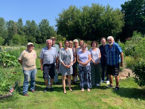 Bildvergrößerung: Eine Gruppe Menschen steht zusammen einem Garten.