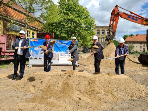 Bildvergrößerung: Im Bild v.l.n.r.: Bezirksstadtrat Frank Bewig, Bezirksbürgermeister Helmut Kleebank, Schulleiterin (komm.) Andrea Malkowski, Bezirksstadtrat Andreas Otti und Nuhi Lusnjani von der beauftragten Baufirma auf der Baustelle mit Helm und jeweils einem Spaten in der Hand