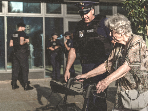 Polizist hilft einer Rentnerin mit Rollator