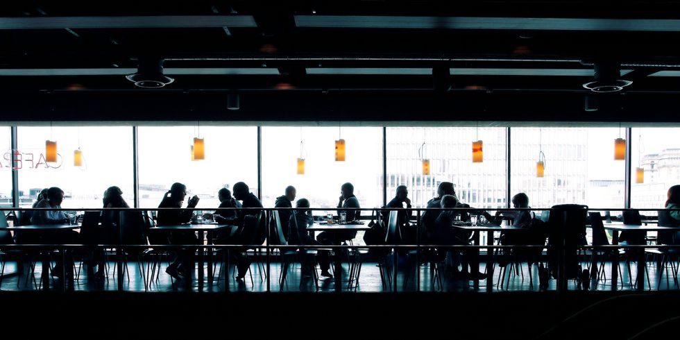 Menschen in eimen Tagescafe sitzend an Tischen.