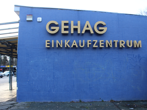 Die Fassade des Einkaufszentrums Britz-Süd ist mit kleinen, quadratischen blauen Fliesen verkleidet. Aufschrift in grau-braun: GEHAG Einkaufszentrum