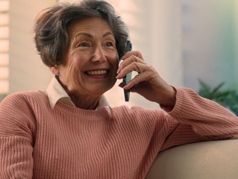 Happy Caucasian old woman carefree middle aged senior lady cheerful smiling retired grandma elderly female granny grandmother talking on smartphone mobile phone talk sharing news on cellphone at home