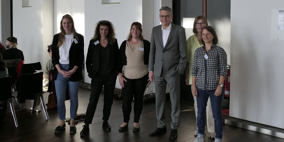 Sechs Personen stehen nebeneinander in einem Saal.