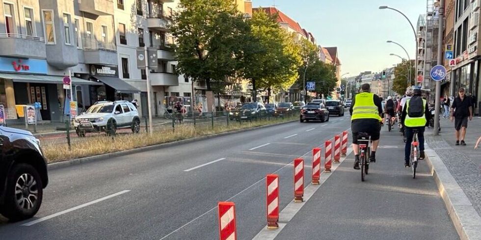 Menschen fahren auf Fahrrädern auf einer geschützten Radverkehrsanlage.