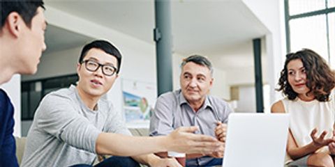 Gruppe Männer und Frau vor Laptop