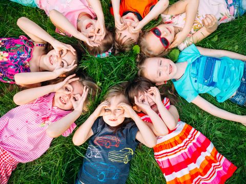 A group of children lying on the green grass in the Park. The interaction of the children.