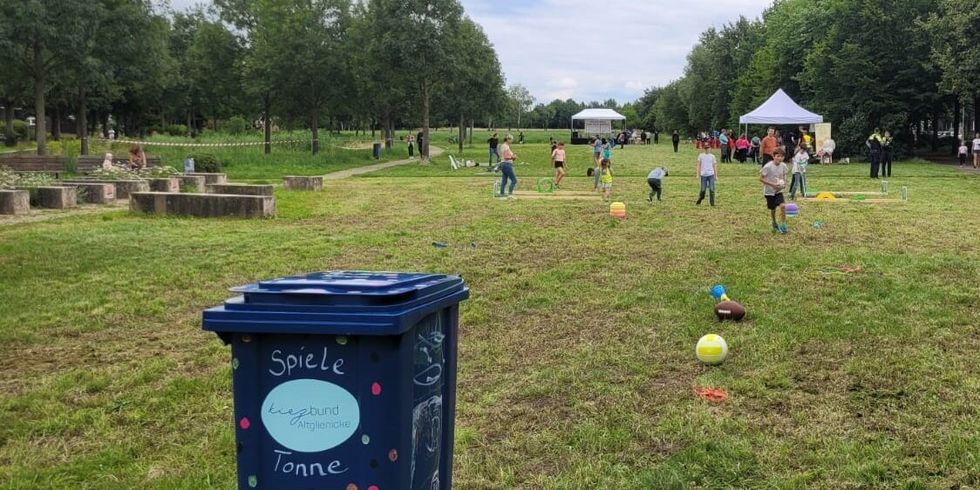 Spieletonne auf einer Wiese mit spielenden Kindern