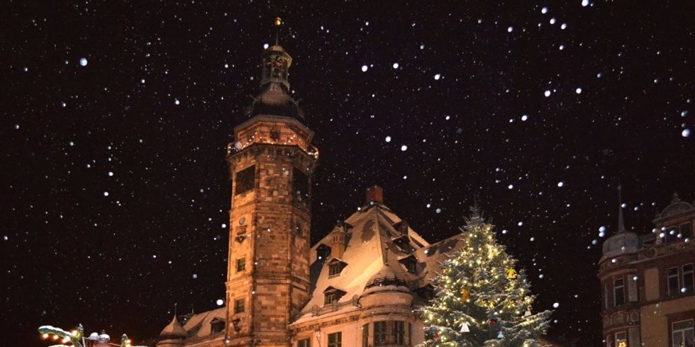 Ein angeleuchtetes Gebäude mit Weihnachtsbaum und Straßenlaterne