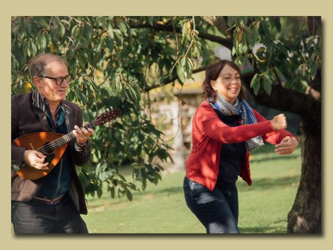 ein Mann spielt Balalaika und eine Frau erzählt dazu