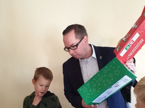 Bildvergrößerung: Schüler Benjamin berät Bezirksbürgermeister Igel bei der Aktion Weihnachten im Schuhkarton