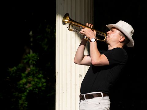 Trompeter mit Hut spielt leidenschaflich auf der Bühne.